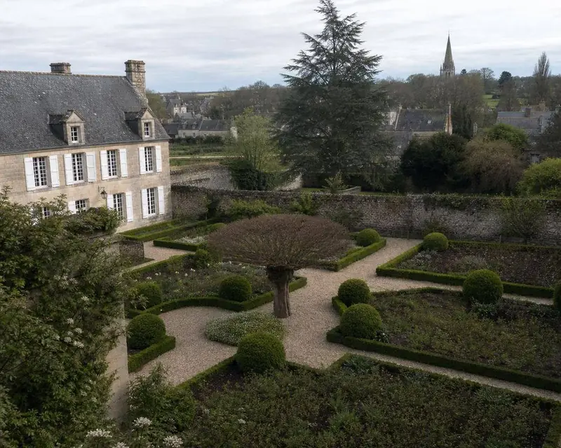 Jardin normand soigné avec arbre taillé en nuage et longère en pierre typique du Caennais